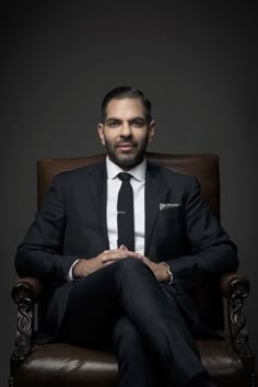 a man sitting in a chair wearing a suit and tie