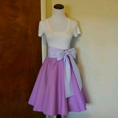 a dress on a mannequin stand in front of a door with a purple bow