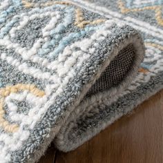 a close up view of a rug on the floor, with wood floors in the background