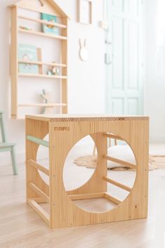 a wooden toy house sitting on top of a hard wood floor next to a green chair