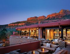 an outdoor dining area with mountains in the background at dusk, surrounded by tables and chairs