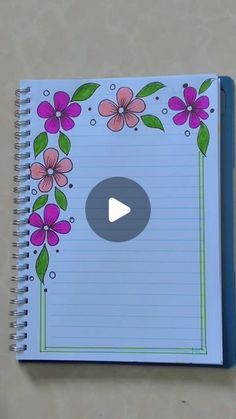 a notebook with pink flowers and green leaves on the cover, next to a pen