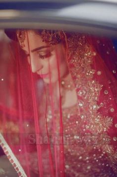 a woman in a red dress and veil is looking out the window of a car