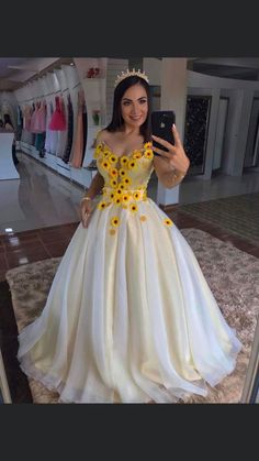 a woman taking a selfie in a white dress with sunflowers on it