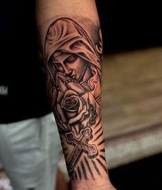 a person with a tattoo on their arm holding a cross and rose in the other hand