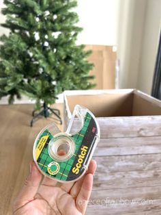 someone is holding up a tape dispenser in front of a christmas tree