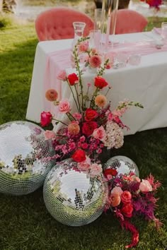 disco ball centerpieces with flowers and greenery on the grass at a wedding reception