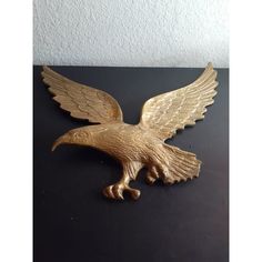 a golden eagle statue sitting on top of a black table next to a white wall