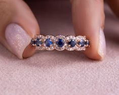 a woman's hand holding a diamond and blue sapphire ring on top of her finger