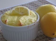 two lemons are sitting next to a small bowl of pudding on a tablecloth