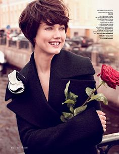 a woman is holding a rose and smiling