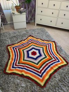 a crocheted rug is laying on the floor in front of a white dresser