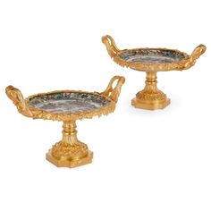 a pair of gold - plated footed dishes with floral designs on the handles and sides