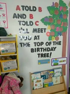 a child's playroom with toys and books on the wall, including a tree