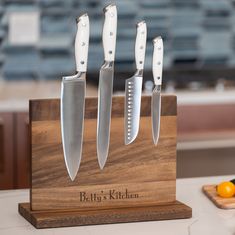 four knives are on a wooden block with the name beth's kitchen