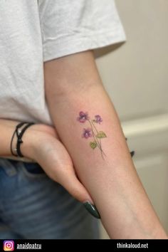 a woman's arm with a small flower tattoo on the left side of her arm