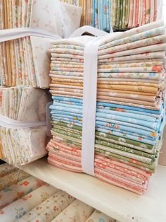 a stack of cloths sitting on top of a shelf next to other folded fabric