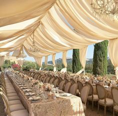 the tables are covered with white draping and place settings for an elegant dinner