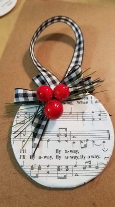 an ornament with two cherries on top of sheet music and red berries