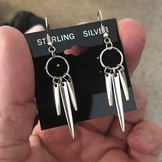 a pair of silver earrings with long spikes hanging from it's earwires