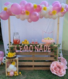 a lemonade stand with pink and yellow balloons on the top is set up for a party