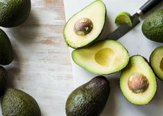 an avocado cut in half on top of a cutting board with a knife