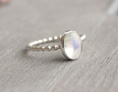 .925 Sterling Silver Ring with 8x6mm genuine rainbow moonstone cabochon. Stackable ring. Band is 1.5mm. This ring is made to order in your size. If you don't see your size available please feel free to message me. All orders ship in a gift box. If you are ordering multiple items and want them boxed separately, please let me know in the notes at checkout. I ship via USPS. Please review the estimated delivery date and processing times. Processing times vary based on how busy my shop is at the time Minimalist Moonstone Opal Ring In Silver, Minimalist Silver Moonstone Ring With Bezel Setting, Modern Sterling Silver Round Moonstone Ring, Minimalist Round Cabochon Moonstone Ring, Nickel-free Silver Moonstone Ring, Minimalist Sterling Silver Cabochon Moonstone Ring, Adjustable Sterling Silver Moonstone Ring, Fine Jewelry, Gift Sterling Silver Nickel-free Moonstone Ring, Silver Moonstone Birthstone Ring, Oval Cabochon