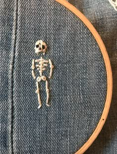 a cross stitched skeleton sitting on top of a piece of denim