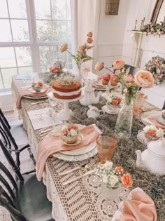 the table is set with cake, flowers and tea cups on it for a bridal party