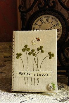 a small white flower is sitting on a table next to an old clock with the words white clover written on it