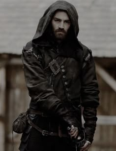 a man with a beard wearing a hooded jacket and holding a knife in his hand