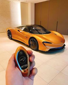 a person holding a cell phone in front of an orange sports car