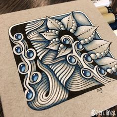 a drawing of an intricate design on a piece of paper with watercolor pencils next to it