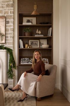 a woman sitting on a chair in front of a book shelf with bookshelves