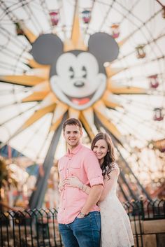 a man and woman standing next to each other in front of a ferris wheel