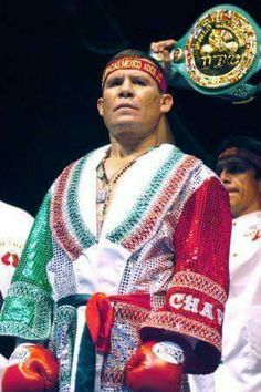 a man with boxing gloves on his head standing in front of two other men wearing colorful outfits