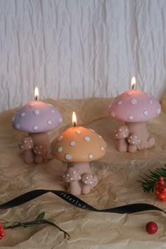 three candles are sitting in front of some mushrooms and berries on a sheet of wax paper