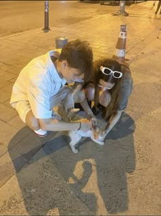 a man and woman petting a cat on the street at night time with words love written in front of them