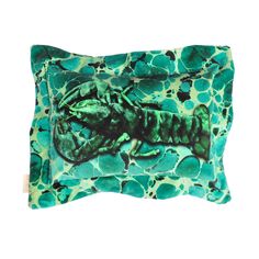 a green and black pillow with an image of a lizard on it's back