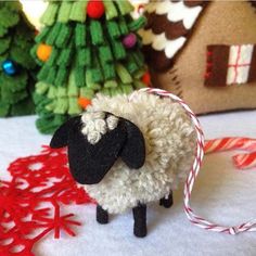 a sheep ornament sitting on top of a table next to a christmas tree