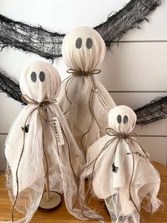 three cloth ghost decorations sitting on top of a wooden table