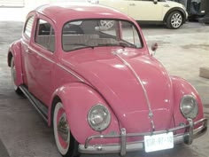 a pink vw bug parked in a garage