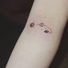 a small tattoo on the arm of a woman with planets and stars around her wrist