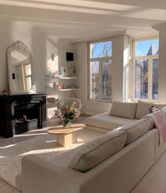 a living room filled with white furniture and a fire place in front of a window