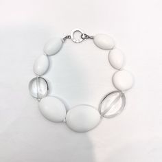 Oval-shaped resin, single-strand clear, and matt white Modern White Adjustable Necklace, Elegant White Glass Necklace, White Resin Necklaces, Elegant White Resin Necklace, Formal White Glass Jewelry, Modern White Lucite Jewelry, White Round Resin Necklaces, Modern White Round Bead Jewelry, Modern White Jewelry With Round Beads