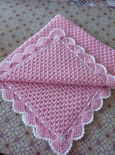 two pink crocheted placemats sitting on top of a table