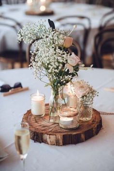 flowers and candles are arranged in mason jars on a wood slice at a wedding reception