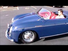 a man driving a blue convertible car in a parking lot