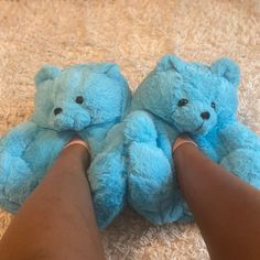 someone is holding two blue teddy bears in their hands on the floor with carpeting