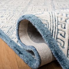 a blue and white rug on the floor with a wooden floor in front of it